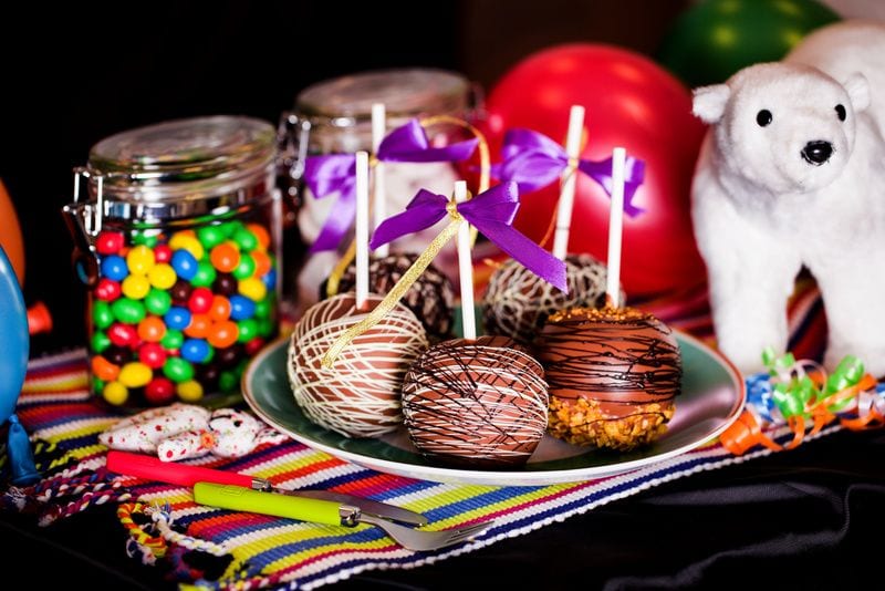 A table with cakepops on a plate and jars of candy in the background
